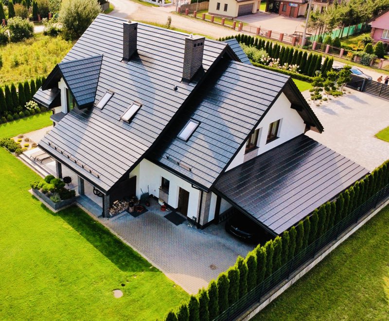 Dom z wielospadowym czarnym dachem sfotografowany z drona
